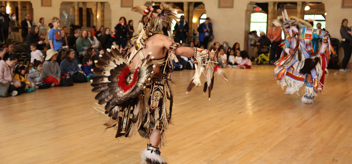 native american dancing in spanish ballroom with feather headress and other native american clothing