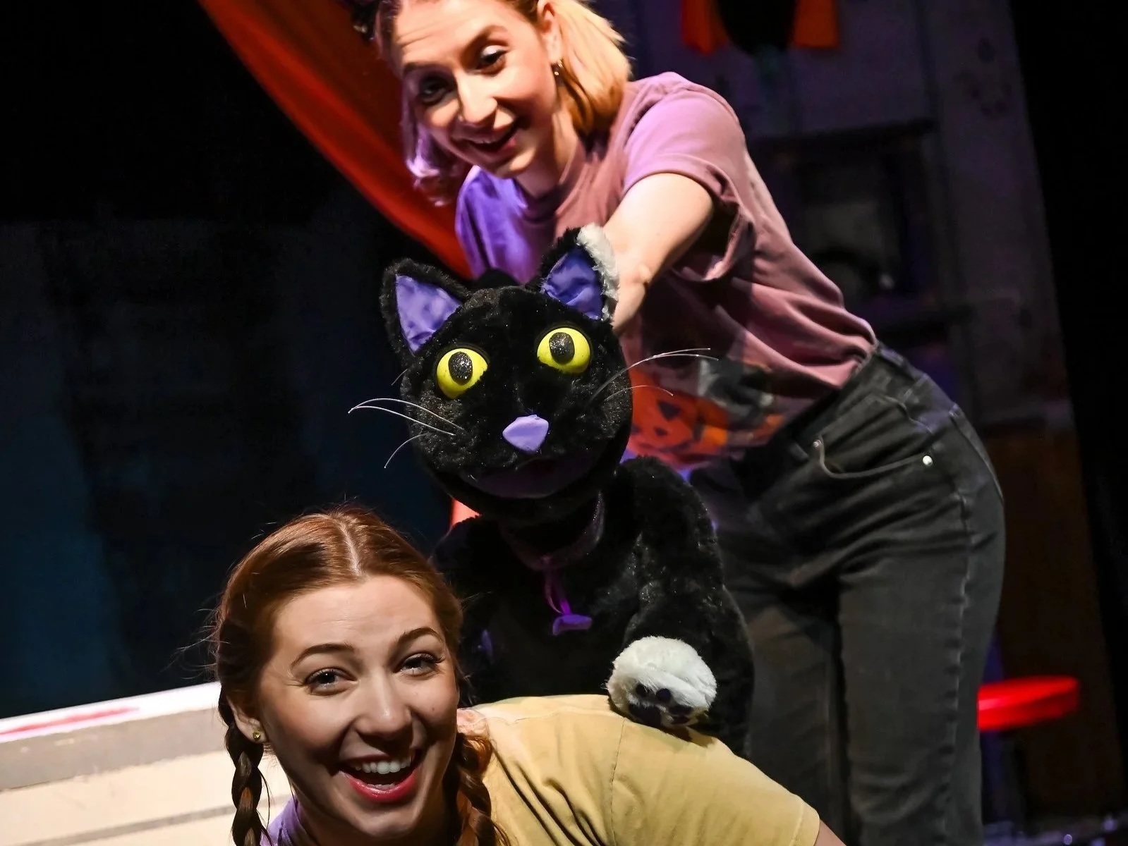 two puppeteers with a black cat puppet