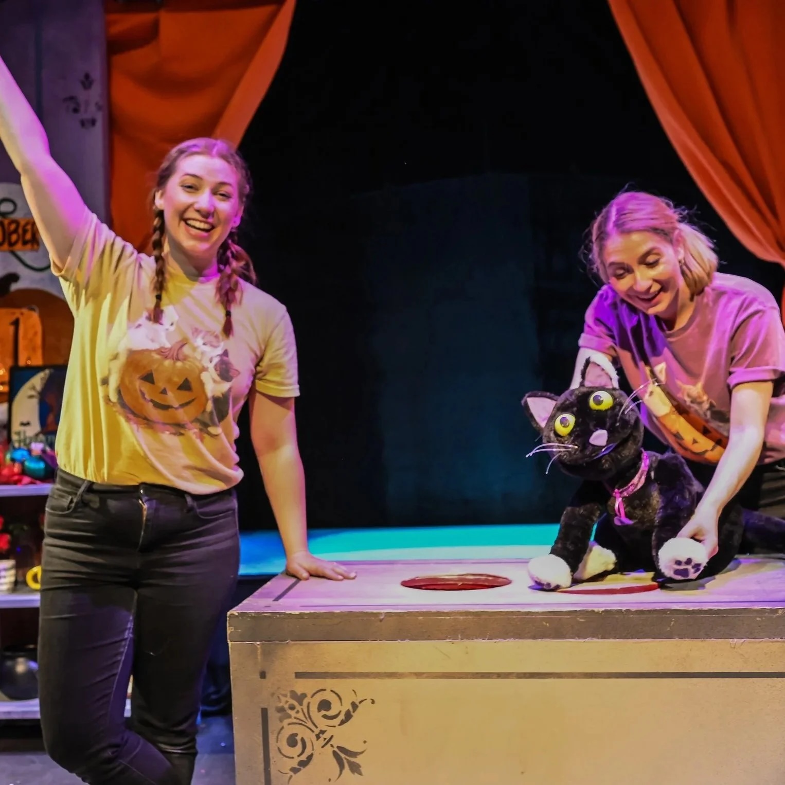 Two women with a cat puppet onstage
