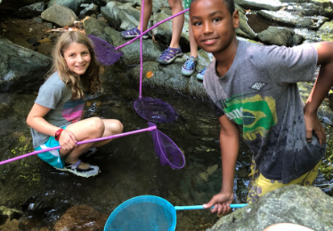 kids outside at a creek with nets