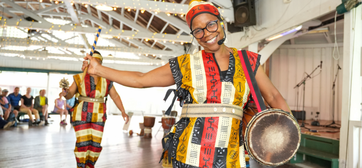 A woman smiles while holding a drum