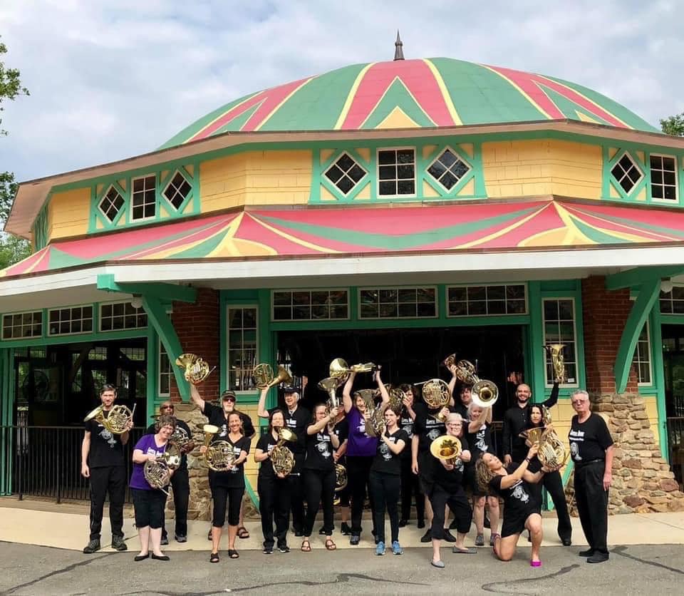 capital horns players with their instruments in front of the carousel