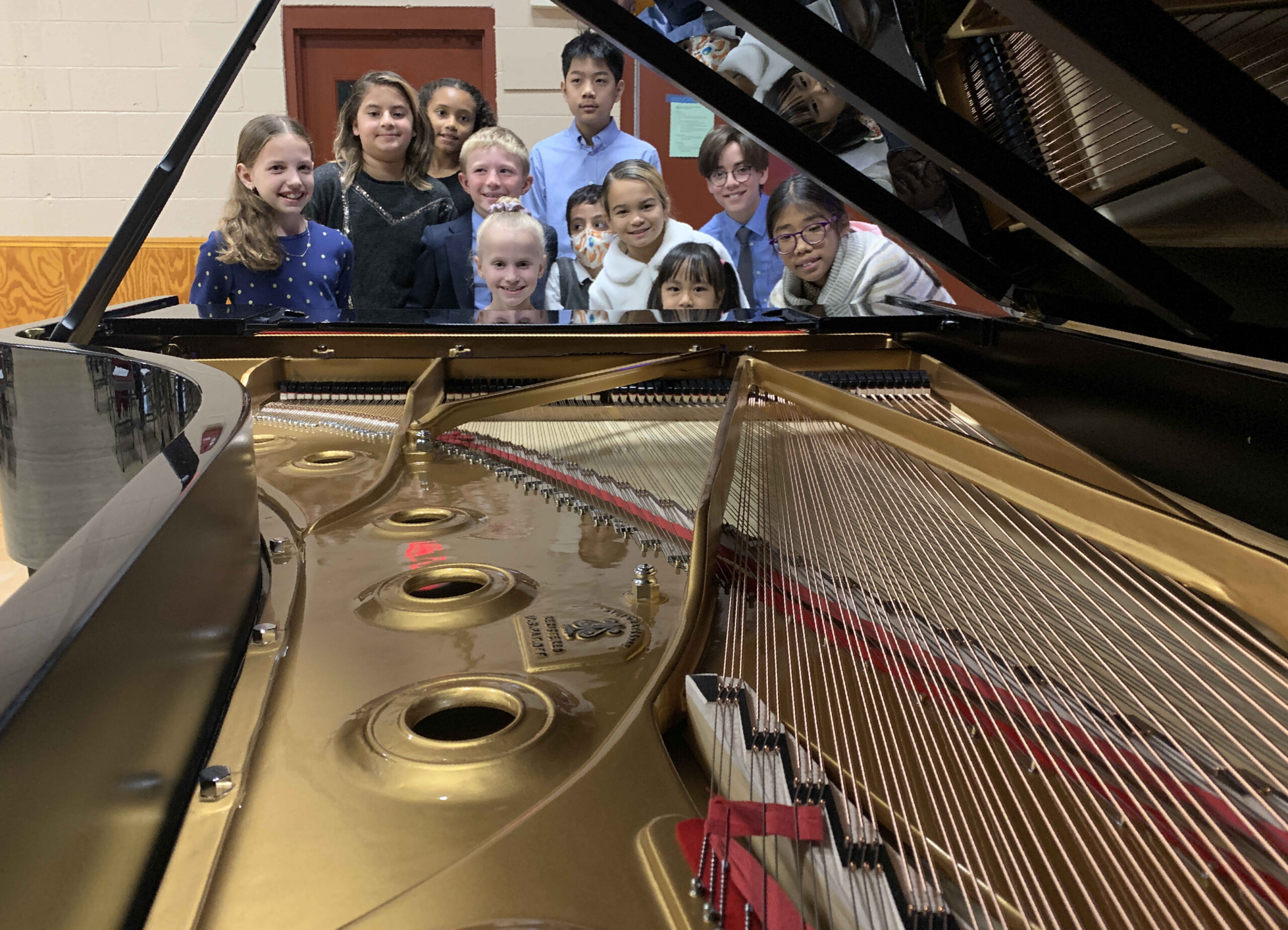 Children looking over strings of grand piano