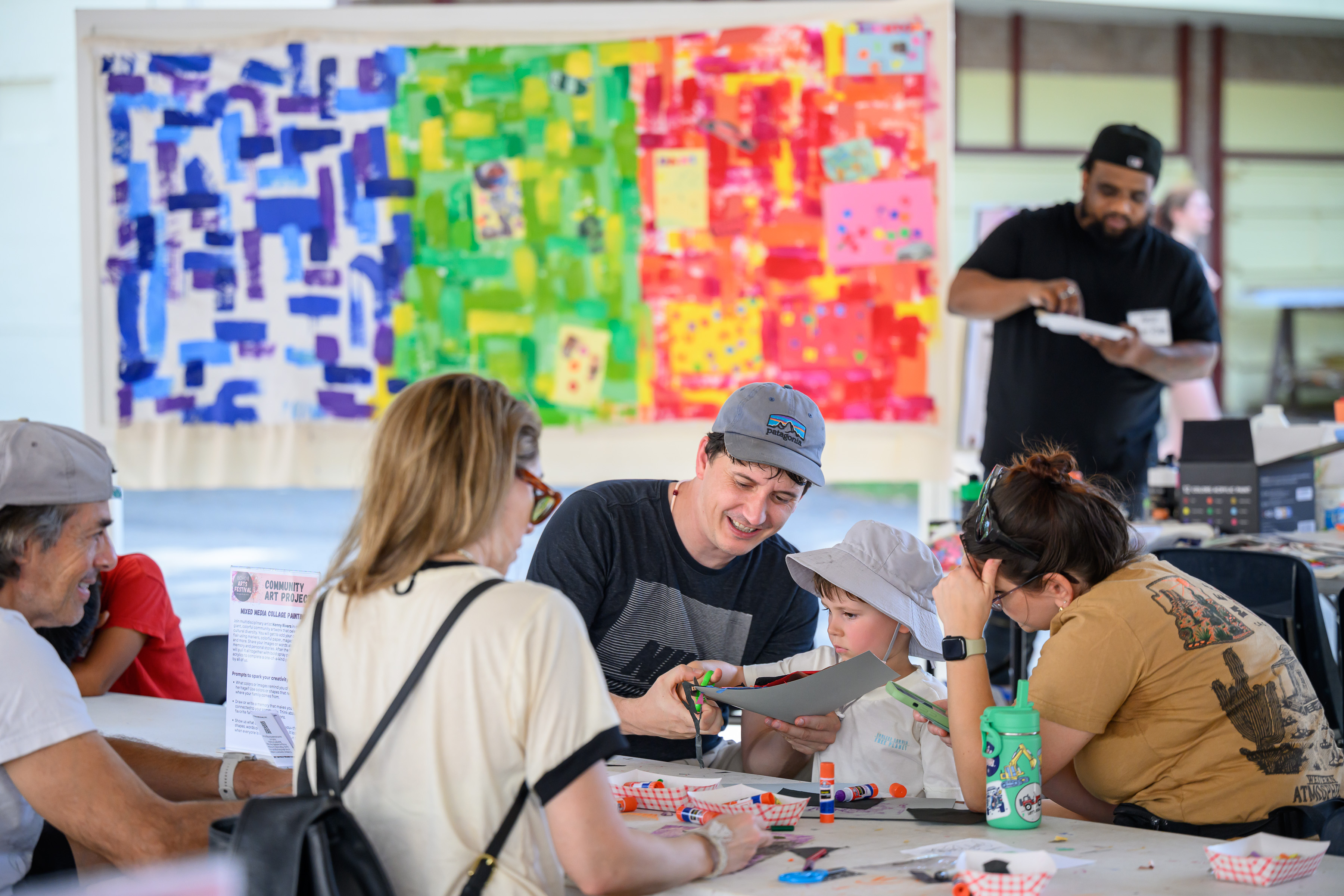 families make arts and crafts with a vibrant mural in the background