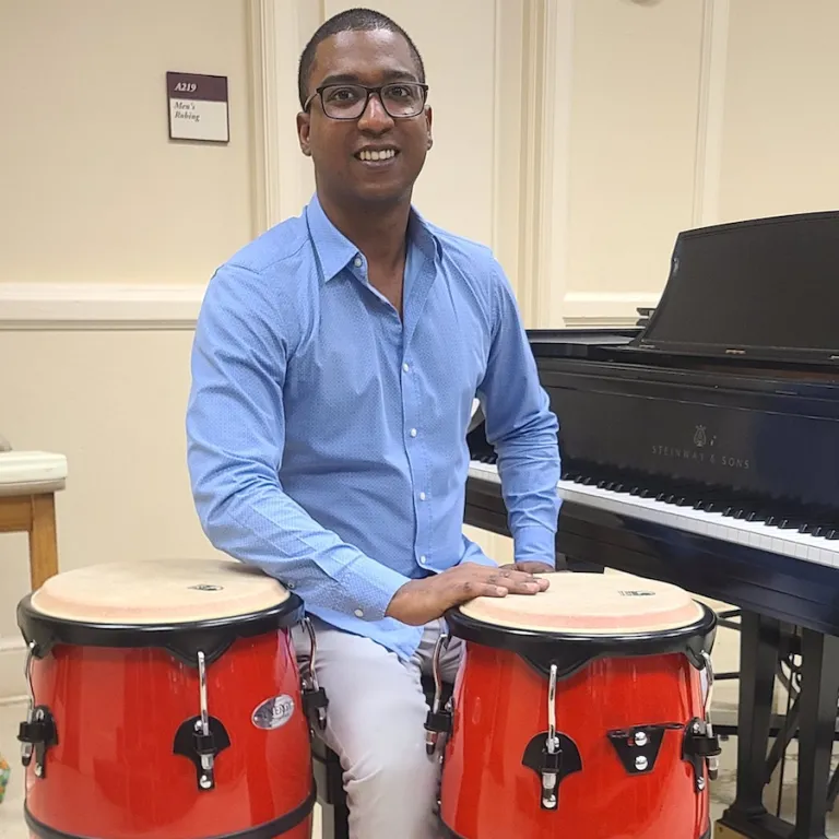 A man sits by drums