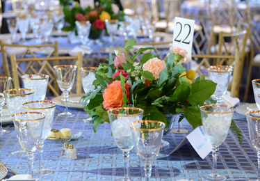 beautiful table set for a gala with crystal and light blue tablecloths and a floral centerpiece