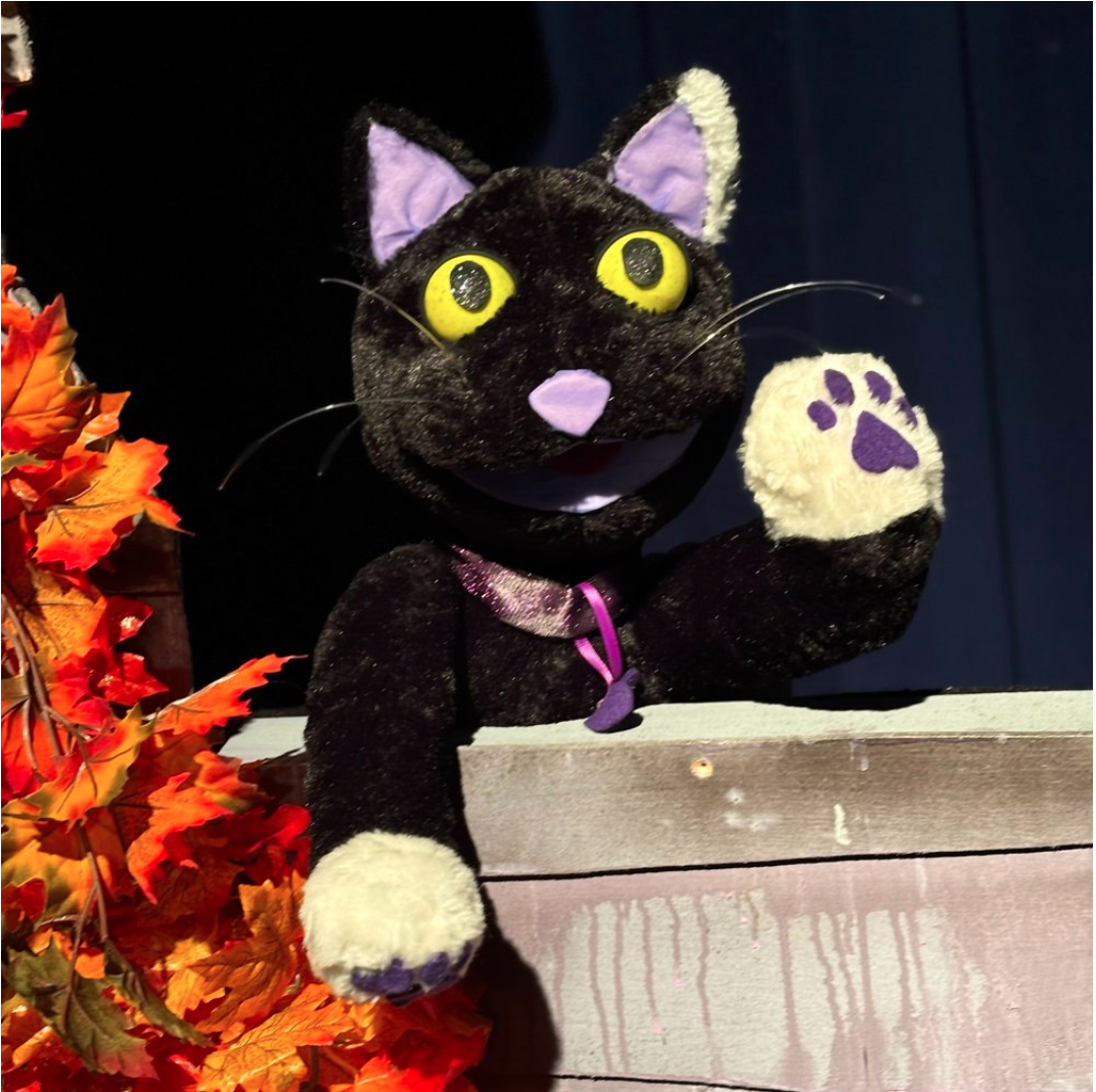 Jennie the Cat, a black cat puppet, waving