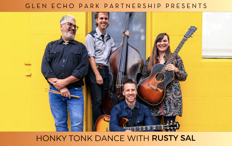 Rusty Sal holds their instruments in front of a yellow brick wall.