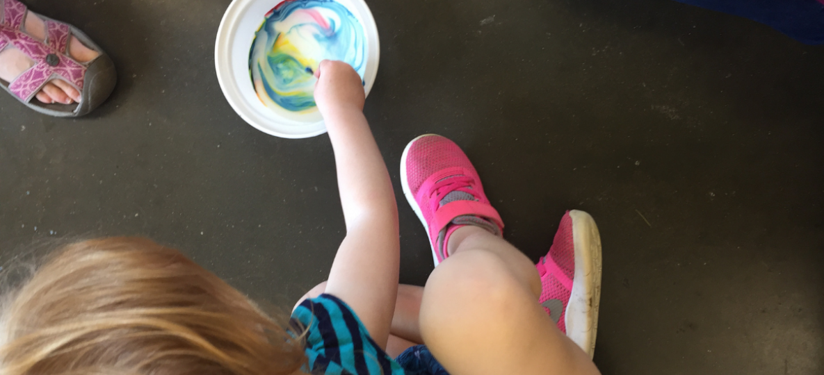 PAGE child with bowl of paint in a colorful swirl.