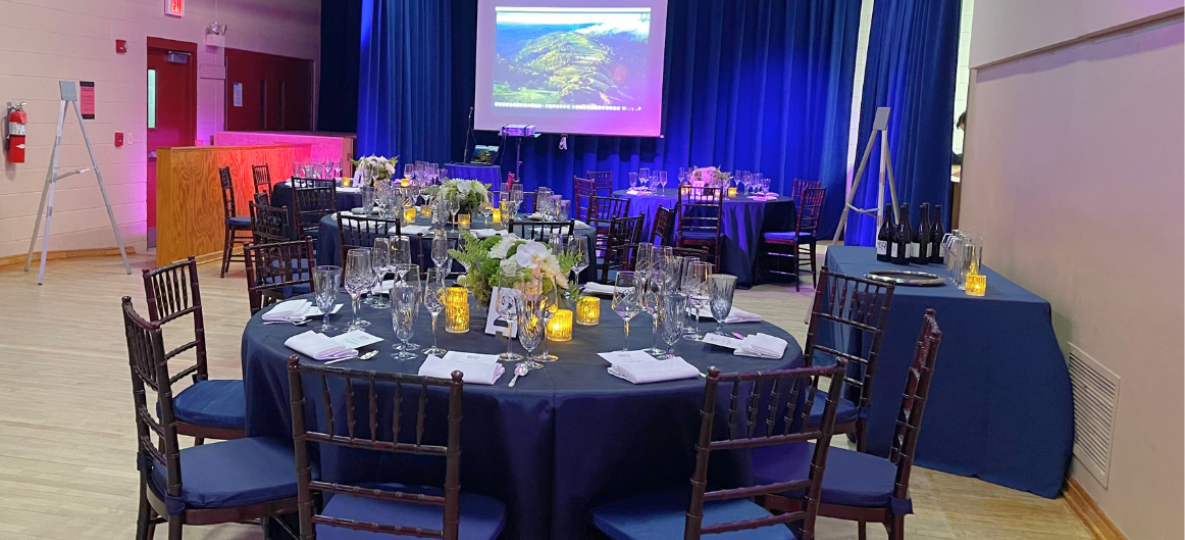 Tables with blue tablecloths in a room with hardwood floors