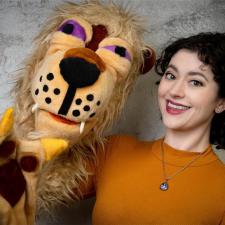 A women holds a lion puppet.