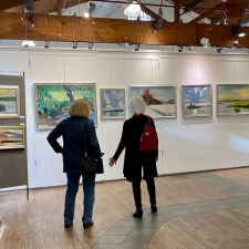 Two visitors stand in front of paintings at the Yellow Barn Gallery