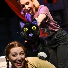 two puppeteers with a black cat puppet