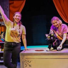 two puppeteers with a black cat puppet