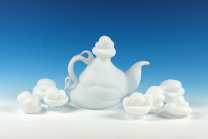 Blown glass teapot with clouds, against a blue gradient backgorund.