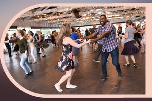 Dancers in Bumper Car Pavilion in featuring Black young man, smiling, in plaid shirt, and White young woman in dark floral dress. image 