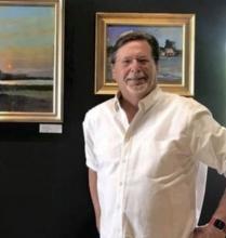 Walt Bartman standing in front of paintings. 