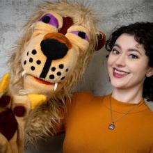 A women holds a lion puppet.