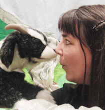 Brunette woman facing a goat puppet.
