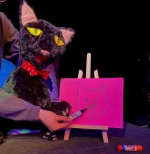black cat puppet drawing a cat face